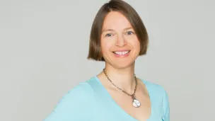 Kvinne i blå genser med ganske kort, brunt hår