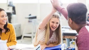 Lys jente og mørk gutt tar "high five"