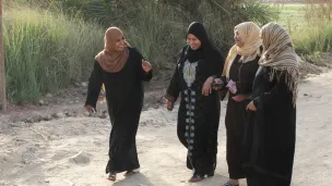 Fire egyptiske kvinner går langs en landevei og prater