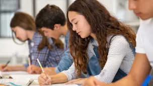 Fire ungdommer sitter i et klasserom og skriver