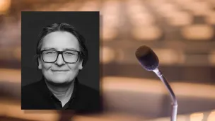 Portrettfoto av Ragnhild Hennum, dekan ved UiO, mot bakgrunn med mikrofon og tomme stolrader