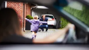Mor sitter i bilen og ser datteren løpe mot far som venter med åpne armer