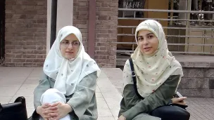 To kvinner med hijab som sitter på en benk