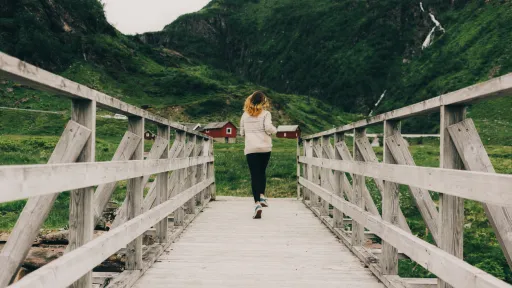Kvinne går over bro på fjellet