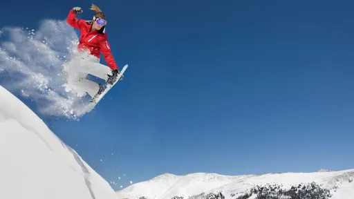 Jente kjører snowboard på fjelltopp