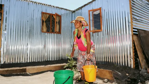 Kvinne henter vann til hjemmet sitt i Klipheuwel i Sør-Afrika 