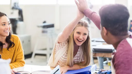 Lys jente og mørk gutt tar "high five"