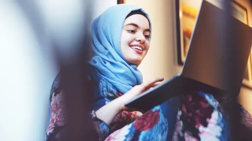 Ung kvinne fra Midtøsten med hijab skriver på pc