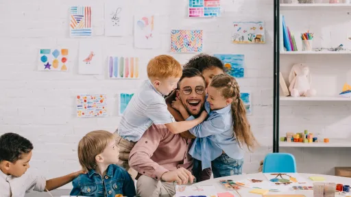 En mannlig lærer blir klemt av tre barn i småskolealder