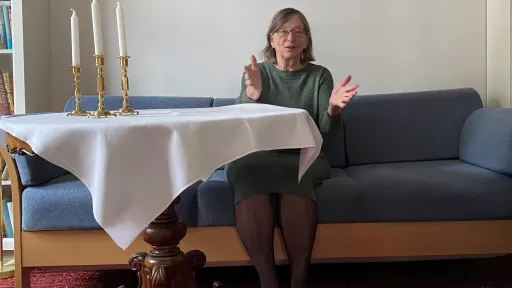 Charlotte Koren sittende i blå sofa ved et bord med hvit duk