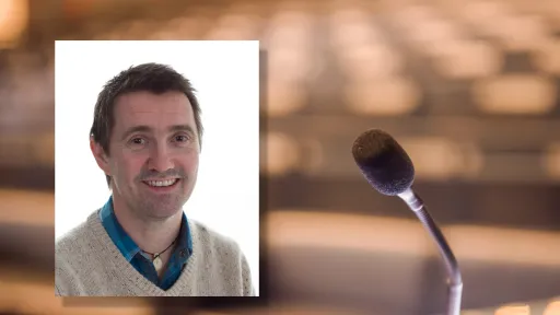 Portrettfoto av Torjer Olsen mot bakgrunn av en mikrofon og et tomt auditorium