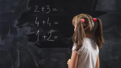 Skolejente med musefletter skriver tall på en tavle