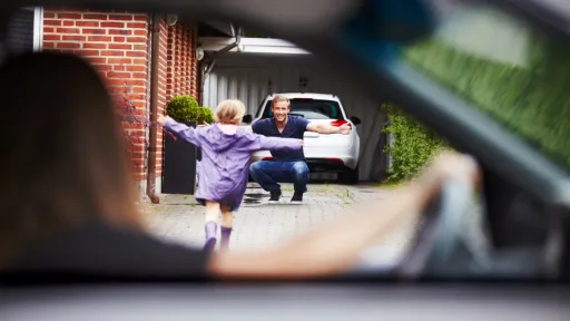 Mor sitter i bilen og ser datteren løpe mot far som venter med åpne armer