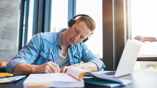 Mannlig student sitter og skriver med headset