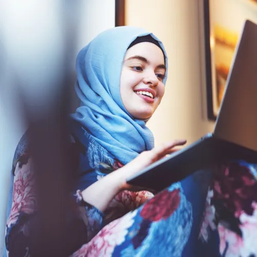 Ung kvinne fra Midtøsten med hijab skriver på pc