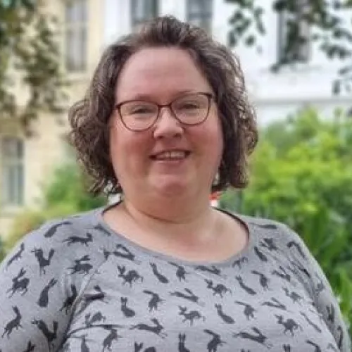Sunniva Árja Tobiasen, stipendiat ved senter for kvinne- og kjønnsforskning ved Universitetet i Bergen fotografert omgitt av grønne trær