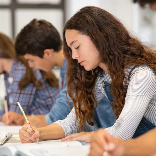 Fire ungdommer sitter i et klasserom og skriver
