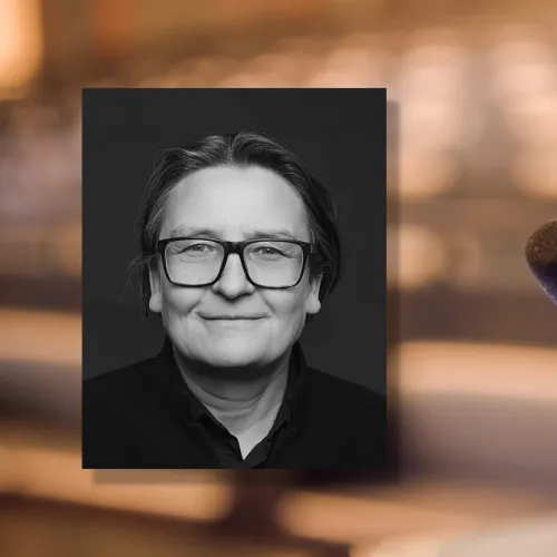 Portrettfoto av Ragnhild Hennum, dekan ved UiO, mot bakgrunn med mikrofon og tomme stolrader