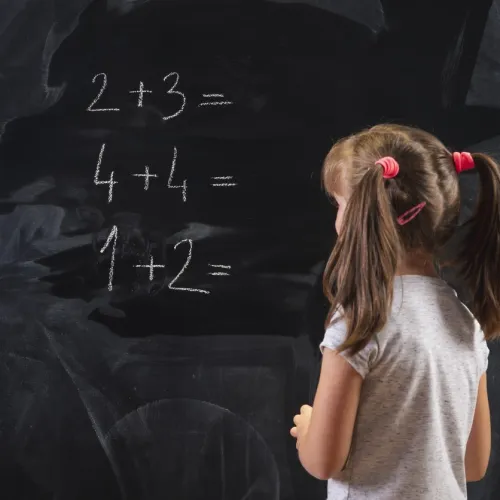 Skolejente med musefletter skriver tall på en tavle