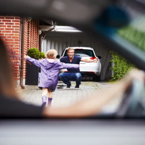 Mor sitter i bilen og ser datteren løpe mot far som venter med åpne armer