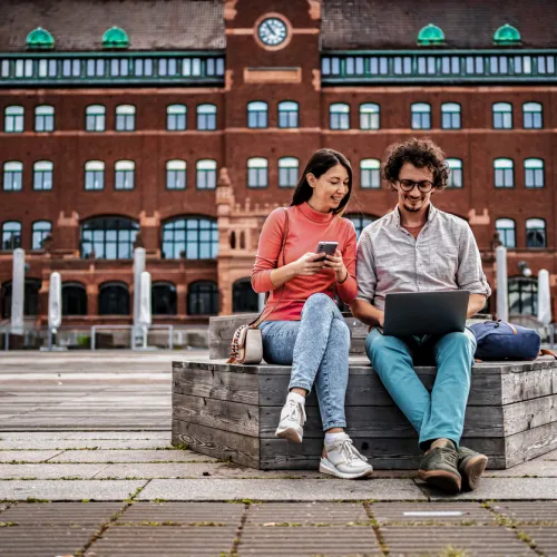 En ung kvinne og en ung mann sitter på en benk i Malmö